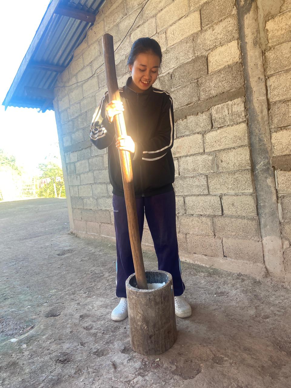 Dokkham au pilon devant la maison familiale