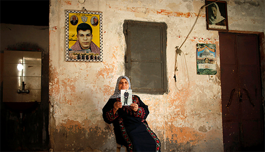 //The mother of Palestinian prisoner Omar Massoud, who has been held by Israel since 1993, displays a picture of him ahead of his release, at his family's house in Gaza City.  (photo by REUTERS/Mohammed Salem)
