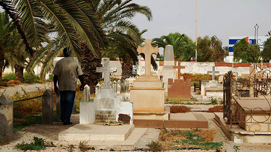 //Father Jonathan passes from tomb to tomb. (Photo by Sana Sbouai).