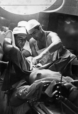 //Le Dr.Georges Burou (à gauche) effectuant une vaginoplastie chez un patient transexuel. On notera que Burou et son assistant, Joachim Cobarro (à droite), sont à peine vêtu, en raison de la température élevée du bloc opératoire . PATRICK JARNOUX /PARIS MATCH / GETTY