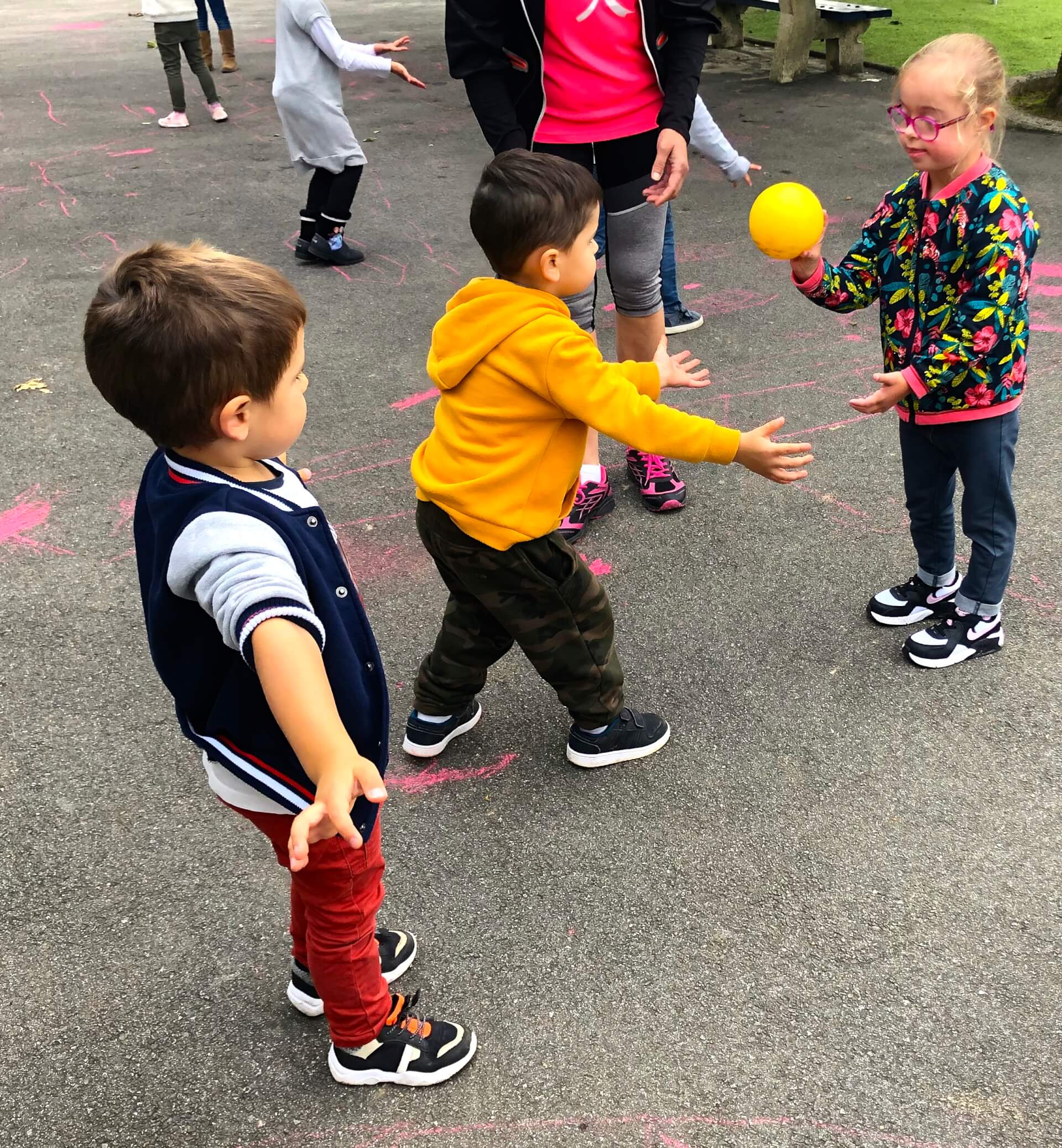 petite fille avec trisomie 21 qui joue avec d'autres enfants dans une cour d'école, qui jouent au ballon. | Trisomie 21 Nouvelle Aquitaine