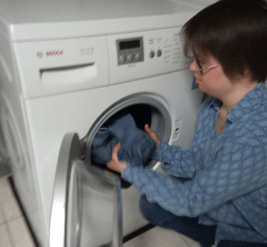 une personne avec trisomie 21 met son linge dans la machine à laver | Trisomie 21 Nouvelle Aquitaine