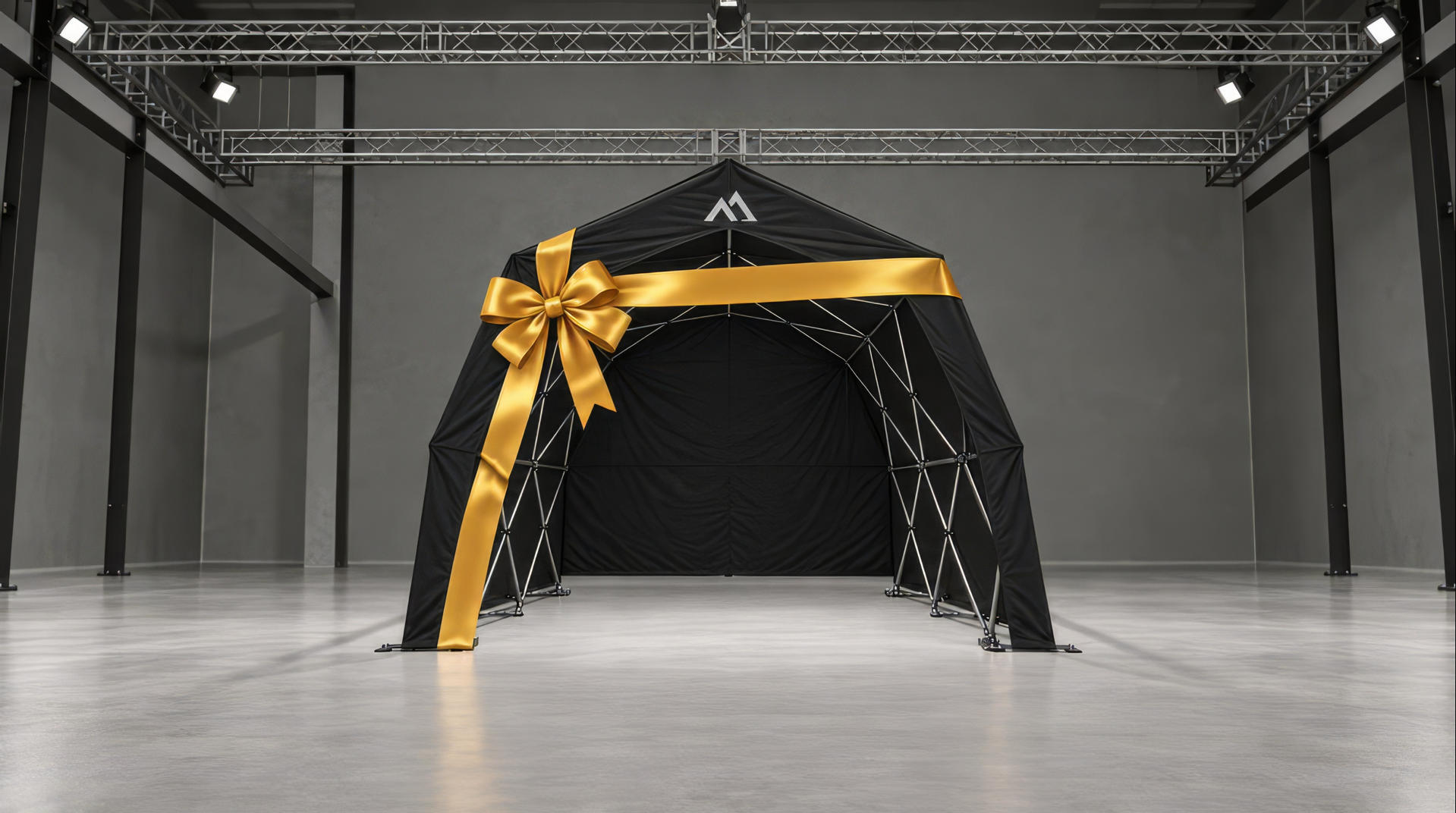 The black Konligo Tent wrapped as a large gift with a gold ribbon, in a concrete hall