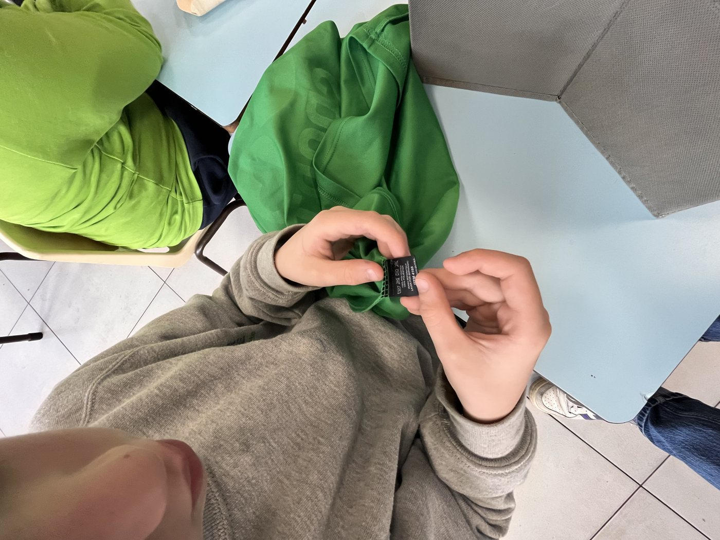 Un élève lit l'étiquette d'un vêtement pour y trouver du plastique