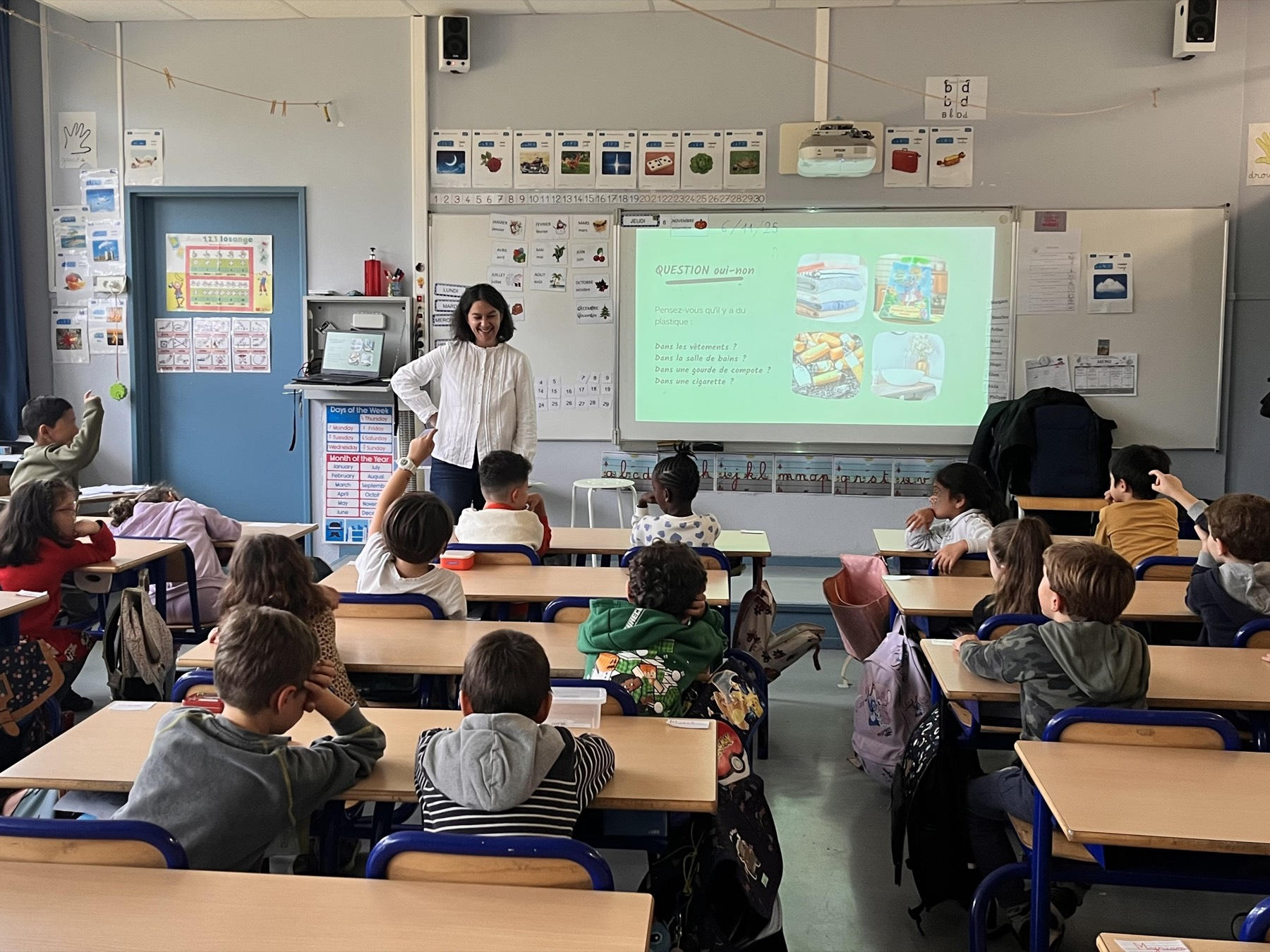 Une intervenante devant une classe d'élèves de primaire, avec au tableau une question oui-non sur le plastique